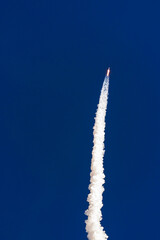 Fototapeta premium Rocket launch against clear blue sky with white trail of smoke