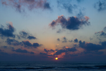 Vibrant ocean sunrise with dramatic clouds over horizon, sun light