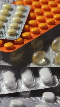 Vertical macro rotation shows blister packs with orange tablets, beige pills and white caplets for medication background