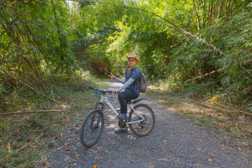 The man is cycling in the forest, solo travel, connecting with nature and him inner self, forest bathing, mindfulness, sustainable development. Net Zero, Carbon Neutral. Photo stock