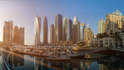 Evening view of the city. Orange sunlight, skyscrapers, buildings, and city streets. On the streets...