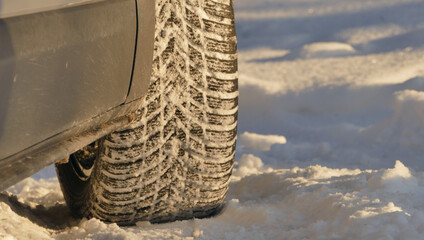 The tread of a car winter tire is completely clogged with snow after an off road drive on snow covered roads
