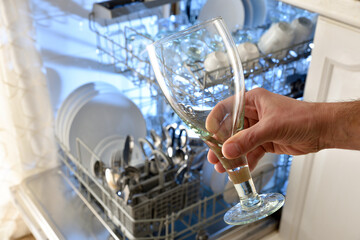 Detail of hand showing freshly washed and bottom dishwasher