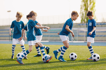 Obraz premium Youth Soccer Dribbling Drill. Kids Practicing Ball Control and Coordination During Outdoor Football Training Session