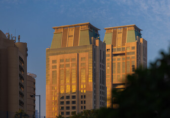 Obraz premium Evening view of the city. Orange sunlight, skyscrapers, buildings, and city streets. On the streets of the Emirates, in a public space.
