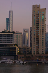Naklejka premium Evening view of the city. Orange sunlight, skyscrapers, buildings, and city streets. On the streets of the Emirates, in a public space.
