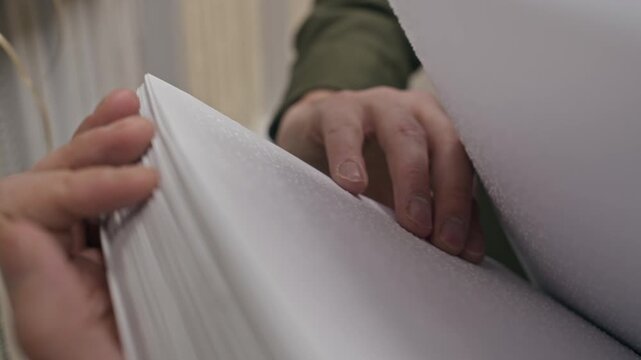 Cropped close up shot of hand of unrecognizable blind person holding braille book and reading tactile pages with fingers at high speed