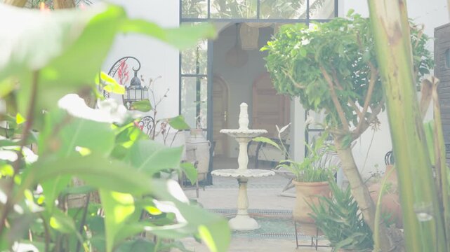 Assilah, Morocco &ndash; May 8, 2024: Orbit shot around a traditional fountain inside a riad in the old Medina of Assilah, surrounded by a small garden and traditional Moroccan architecture.