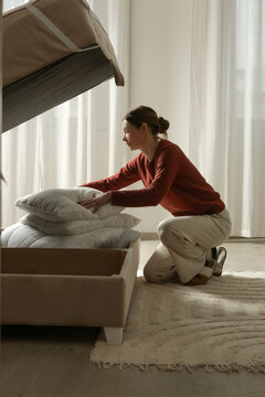 Seasonal Home Organization &ndash; Woman Storing Pillows and Winter Duvets in Under Bed Storage for Following Spring Summer season