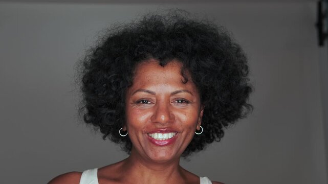 Expressive middle adult woman smiling and talking at camera on gray background