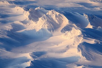 Powerful winter gusts form snowbanks while sunlight and shadows accentuate the icy terrain