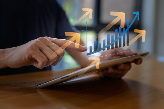Business professional using tablet with rising growth chart and upward arrows, representing business success, financial performance, revenue growth, data analysis and strategic planning concept. - Powered by Adobe