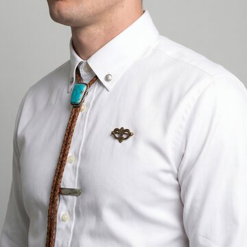 Man wearing bolo tie and brooch on white shirt, close-up