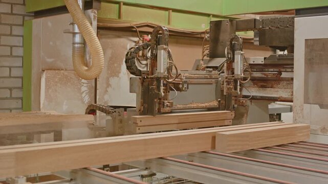A CNC woodworking machine delivers a cut frame and automatically grabs a fresh wooden beam for processing,