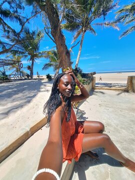A beautiful young African woman taking a selfie on the beach