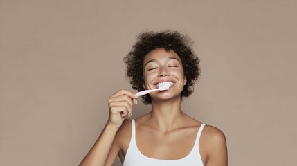 Obraz premium Joyful woman brushing teeth with pink toothbrush on a neutral background