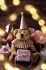 Vintage style teddy bear wearing paper ruff collar and a cap sitting with present