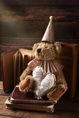 Vintage style teddy bear wearing paper ruff collar and a cap sitting with a heart