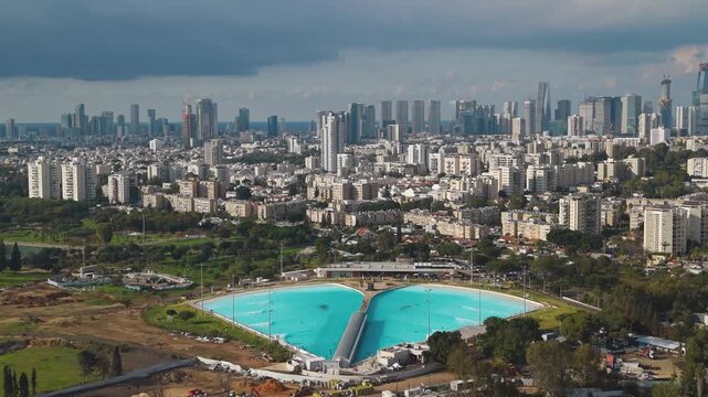 Surfing lagoon in South Tel Aviv with the city's old neighborhoods and modern skyscrapers visible in the background.