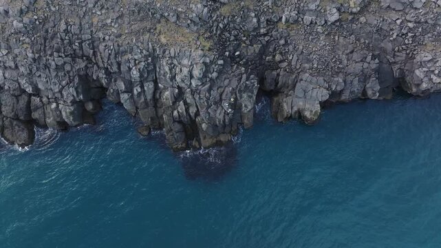 Top down aerial of calm Icelandic waters, basaltic rocks on shoreline - Atlantic tide