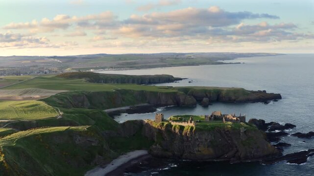 Aerial view of Dunnottar Castle ruins perched on cliffs along the coast, where dark waters meet the rugged shoreline, Stonehaven, Scotland, United Kingdom.