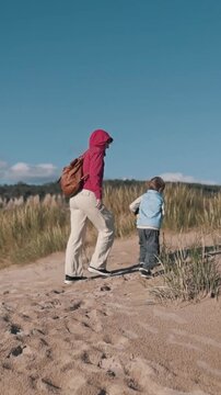 Mother and son walking on sand dunes