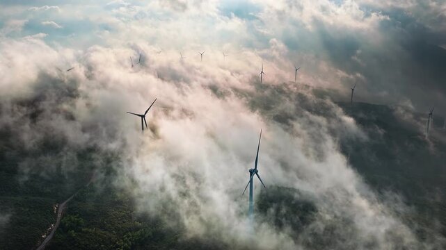 Aerial shot of many wind turbines on a misty mountain ridge generating green energy in the morning