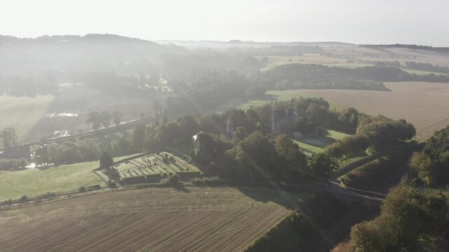 Aerial view of a church and a castle surrounded by trees and green fields under a misty sky, Cupar, Scotland, United Kingdom.