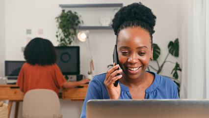 Happy Professional on Phone in Bright Modern Office With Team Member at Desk