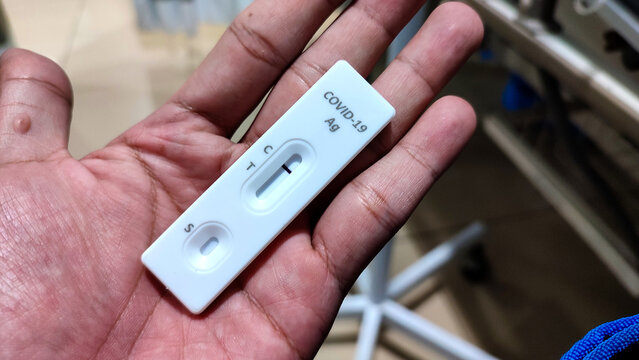 Close-up of a hand holding a COVID-19 rapid antigen test cassette showing a single control line, indicating a negative result. Suitable for healthcare, medical testing, and health screening concepts.