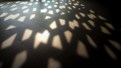Abstract Islamic background featuring sunlight filtering through a patterned screen, casting geometric shadows on a tiled floor. Minimalist and serene, perfect for Ramadan or Islamic design concepts