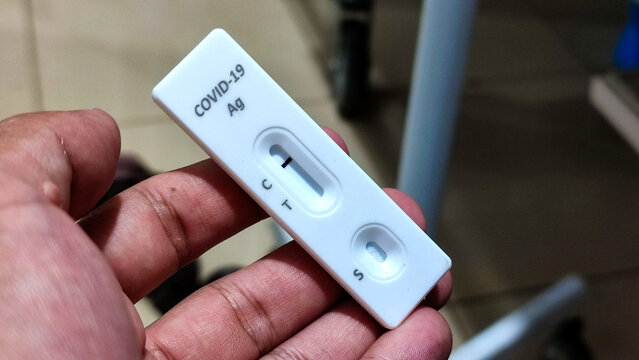 Close-up of a hand holding a COVID-19 rapid antigen test cassette showing a single control line, indicating a negative result. Suitable for healthcare, medical testing, and health screening concepts.