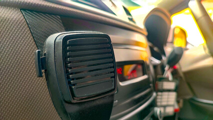 Close-up of a handheld radio microphone mounted on an ambulance dashboard with the interior controls blurred in the background. Emergency communication and first responder equipment concept.