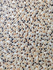 Fototapeta premium Decorative pebble stone floor with rounded natural stones in tan, brown, grey, and black tones, creating organic textured surface ideal for backgrounds, landscaping, and architectural design concepts