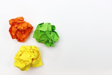 Three crumpled color paper orange, green and yellow, white background