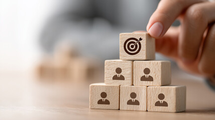 Hand putting wooden cube block on top pyramid with goal icon for business strategy and talent management concept