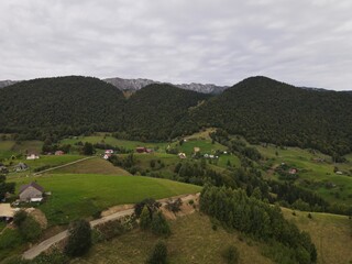 Obraz premium Aerial View of Rural Mountain Village with Forested Hills and Farmland