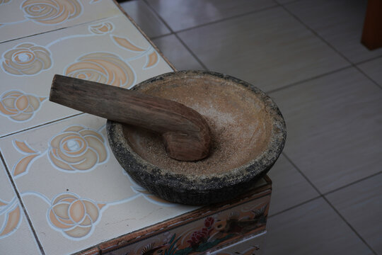 Traditional stone cobek paired with a wooden ulekan mortar and pestle. Indonesian kitchen utensil, food preparation, and culinary heritage concept.