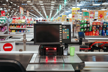 Modern supermarket checkout terminal with screen, barcode scanner, red light, and conveyor belt in...