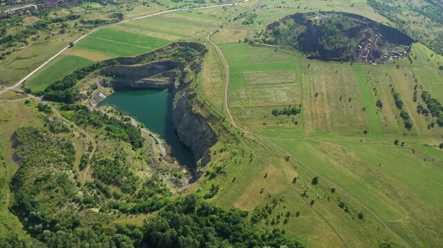 Aerial view of the Racos Volcano crater lake showing the striking contrast between the turquoise water and the rugged terrain, Racos, Judetul Brasov, Romania.