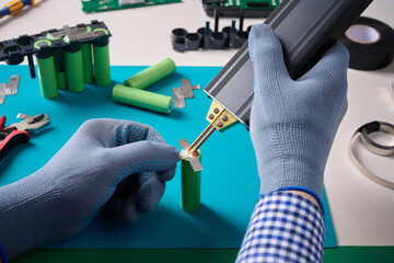 A man spot welds nickel tape a battery assembly. Battery cell module block on the platform.