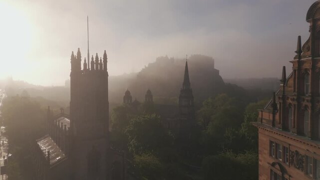 Aerial view of a majestic church with a tall spire and Edinburgh Castle in the misty background under a soft, diffused light, Edinburgh, Scotland, United Kingdom.