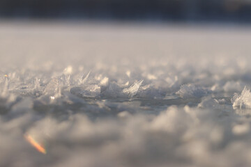Frozen river covered with ice and snow, side view with selective focus. Snow sparkles in the sun. Frozen surface of a river or lake covered with snow, sparkling snow crystals. Winter landscape