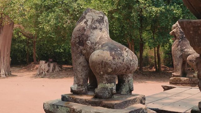Ancient stone lion guardian statue standing on pedestal at Angkor Wat in Cambodia, showing sacred symbolism, weathered surface, and cultural heritage