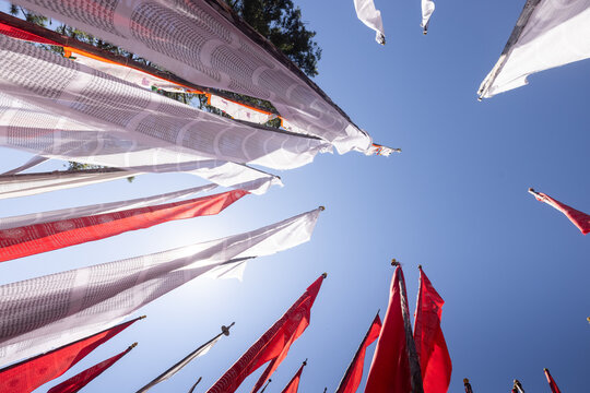 View of vibrant prayer flags fluttering against the azure sky, a symphony of red and white creating a spiritual ambiance, Kiki La Pass, Bumthang, Bhutan.