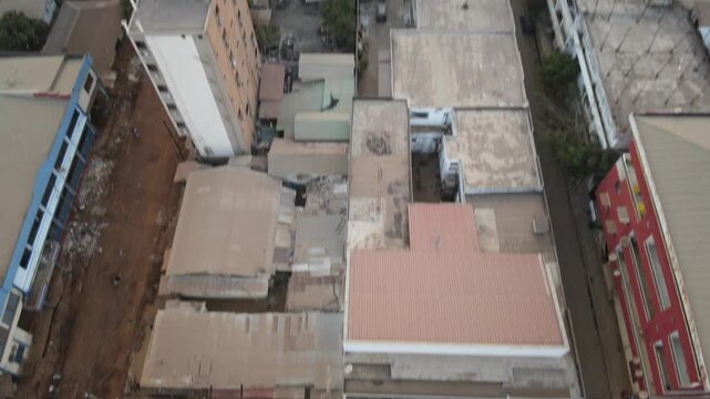 Aerial view of a bustling street market scene, contrasting earthy tones of the ground with colorful stalls and human activity, Conakry, Conakry, Guinea.