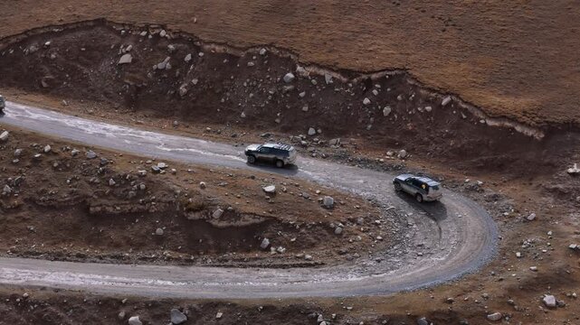 SUVs Taking Hairpin Turn On Mountain Gravel Road Aerial View