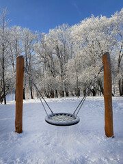 Snow-covered swing in the winter. European winter, snowfall, natural disasters.