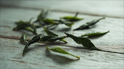 Obraz premium Close-up of fresh tea leaves on a rustic wooden surface, bathed in soft natural light with a blurred background.