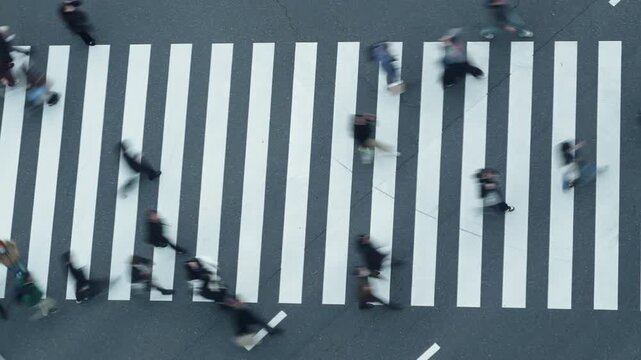 Top down view of isolated people walking across a zebra crossing.